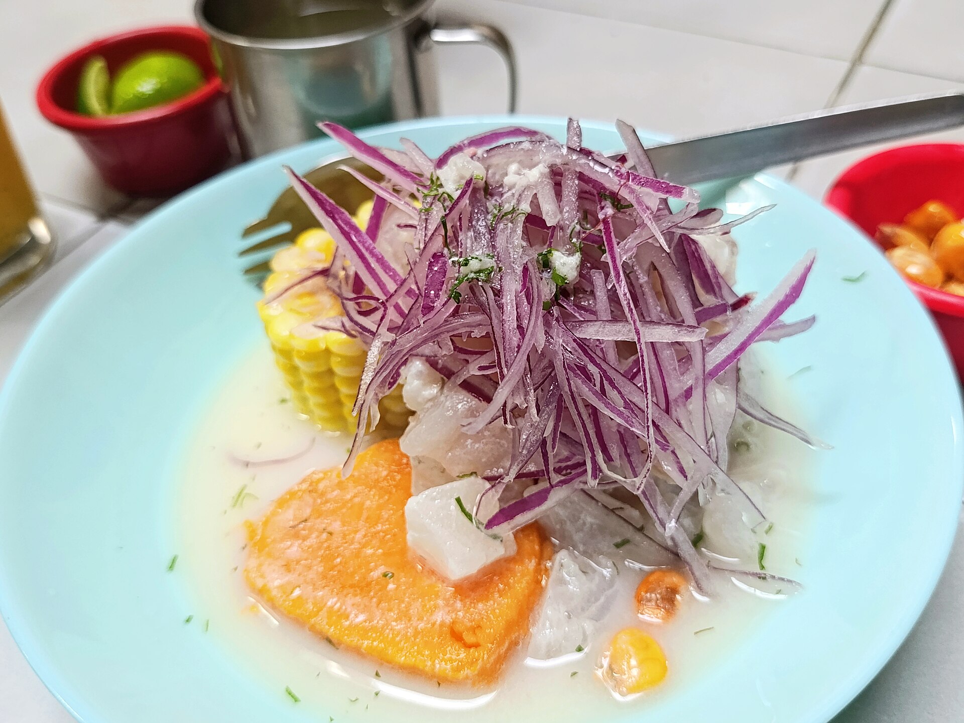 A bright plate of Peruvian ceviche with red onion, sweet potato and corn